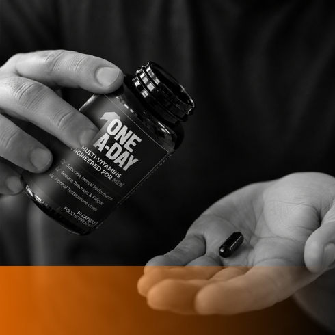 Person taking a One A-Day multivitamin capsule from the bottle