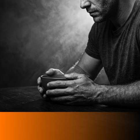MenTools blog feature image for meal prep versus eating out for busy men, black and white close-up photograph of a man's hands around a bowl at a dark table, orange MenTools overlay band